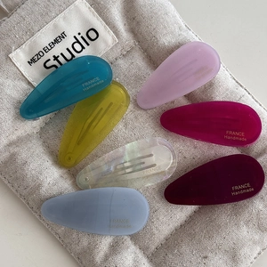 Detail showing set of six colorful acetate water drop hair clips with gold handmade stamp