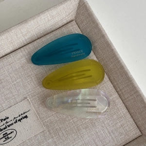 Detailed macro of teardrop acetate hair clips in blue, yellow and pearlescent white