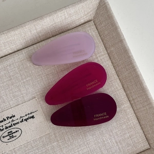 Detail view of handmade water drop acetate hair clips in three purple gradient colors
