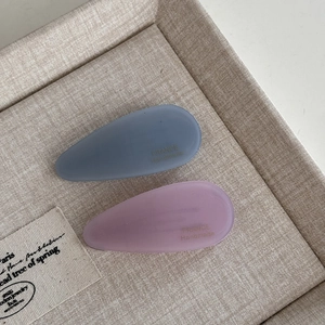 Macro detail of matte acetate waterdrop hair clips in blue and pink with handmade text