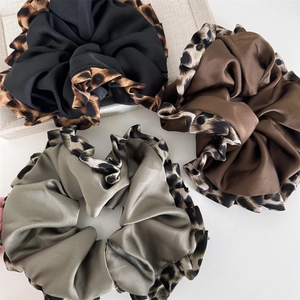 Three elegant satin leopard print scrunchies in black, chocolate brown and sage green colors