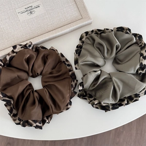 Detail of satin leopard print scrunchies in dark brown and olive green colors