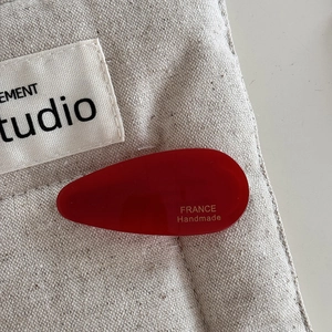 Close-up of red acetate water drop hair clip with gold France Handmade lettering