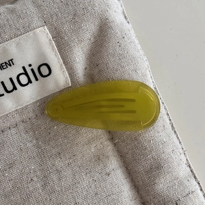 Detail view of a translucent yellow teardrop acetate hair clip with metal spring clip