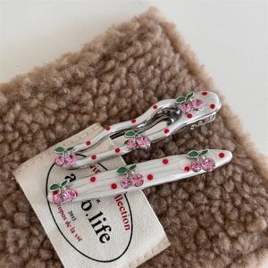 Detailed close-up of cherry hair clips with pink rhinestones and red polka dots