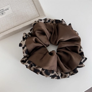 Close-up of a large satin scrunchie featuring dark brown fabric and leopard print edges