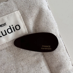 Detail of a dark brown acetate teardrop hair clip with a gold FRANCE Handmade logo