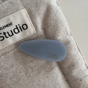 Close-up of a matte gray-blue acetate waterdrop hair clip on a canvas background