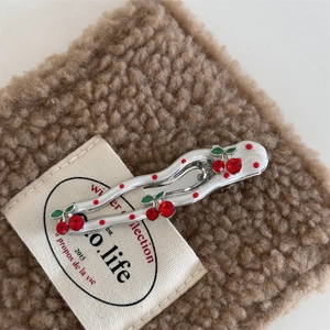 Close-up of cherry hair clip with red crystals and polka dots on soft brown fleece