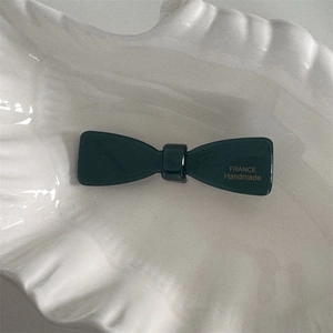 Détail de la pince à cheveux nœud en acétate vert foncé avec inscription dorée faite main