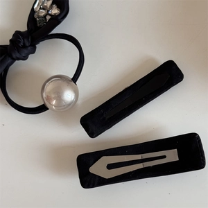 Detail of silk bow hair tie with silver metallic sphere and matching black hair clips