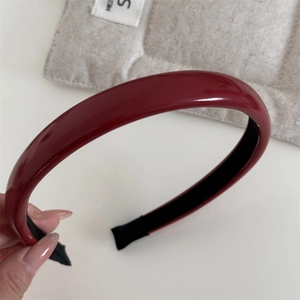 Détail du serre-tête en cuir verni rouge montrant la surface brillante et le tissu intérieur