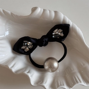 Detail of black satin bow hair tie with sparkling rhinestones and a champagne gold bead