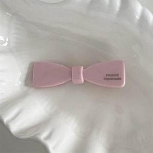 Détail d'une pince à cheveux nœud en acétate rose avec logo doré France Handmade