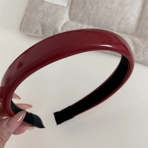 Détail du serre-tête en cuir rouge brillant montrant la texture lisse et la doublure noire