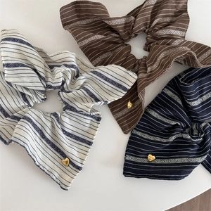 Close-up of vintage striped scrunchies in three colors with gold heart charms