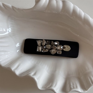 Close-up of black satin hair clip with sparkling rhinestones and a silver heart charm