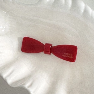 Détail de la pince noeud en acétate rouge montrant la gravure dorée France Handmade