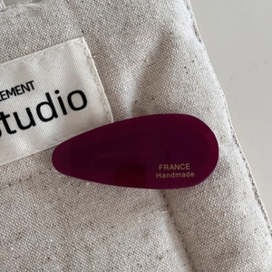 Detailed macro view of a handmade plum purple acetate water-drop hair clip on canvas