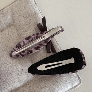 Détail de barrettes à motif léopard rose avec nœud et pinces crocodiles en métal