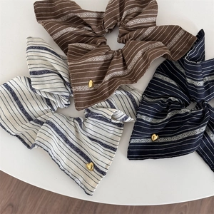 Close-up of striped scrunchies with golden heart charms in brown and beige tones