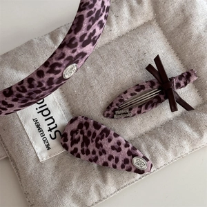 Détail d'un ensemble d'accessoires de cheveux léopard rose sur fond en tissu texturé