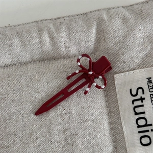 Dettaglio di un fermaglio per capelli bordeaux a pois con fiocco su sfondo di lino