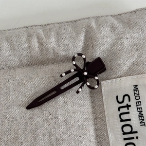 Dettaglio di un fermaglio per capelli a fiocco marrone scuro con pois bianchi su tessuto