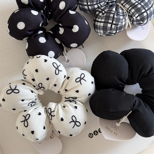 Detail of four black and white fabric scrunchies with polka dots and plaid patterns