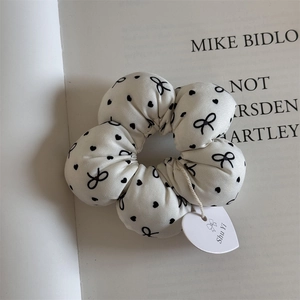 Close-up of white scrunchie with black bows and hearts on a vintage book page