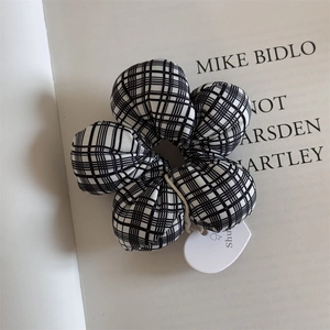Detail of a black and white checkered flower hair tie with a white heart tag on an art book