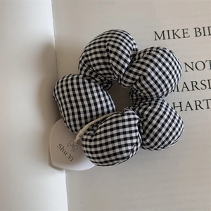 Detail of black and white checkered scrunchie hair tie with small heart brand tag