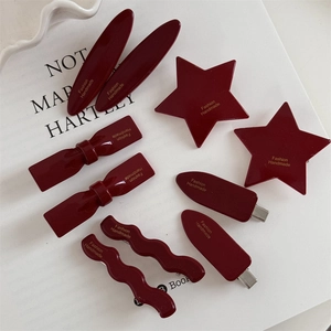 8-piece set of wine red festive hair clips with stars and bows on white ceramic plate