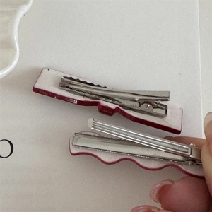 Detail view of the silver metal alligator clip and dual-layer red and white backing