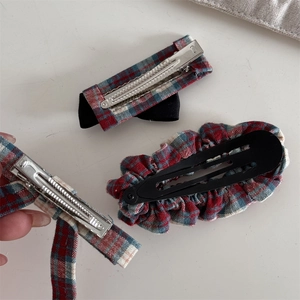 Detail of red and green plaid hair clips set showing back construction and fabric texture