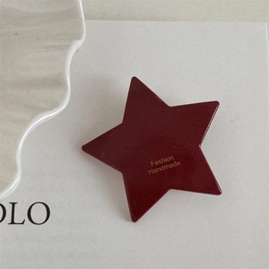 Close-up of a handmade burgundy star-shaped hair clip with gold fashion lettering