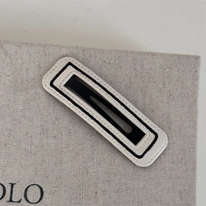 Nahaufnahme der minimalistischen Haarspange aus Leder in Schwarz und Beige mit Ziernaht