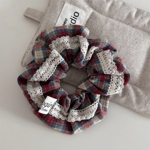 Detail of red and blue plaid hair scrunchie with delicate white lace trim and tag