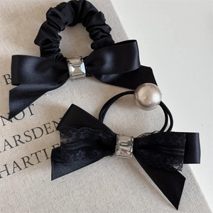 Detail of black satin scrunchie and lace bow tie with clear rectangular crystal accents