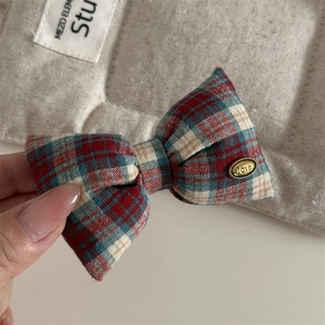 Detail of red and navy plaid bow hair clip with gold love engraved metal buckle