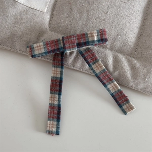 Detailed macro view of vintage red and green plaid fabric bow hair clip texture