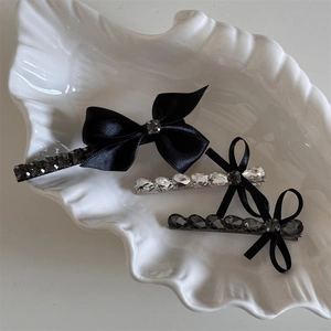 Ensemble élégant de pinces à cheveux noires avec strass sur un plateau coquillage