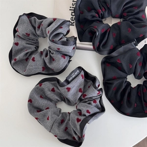 Close-up of heart print scrunchies with Blind For Love labels on a minimalist magazine