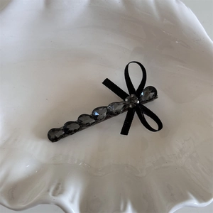 Vue détaillée d'une barrette à nœud noir ornée de cinq strass gris en goutte d'eau