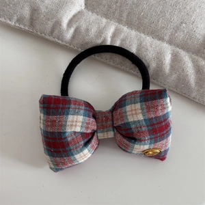 Detail of red and blue plaid bow hair tie with a gold metal plate engraved with love