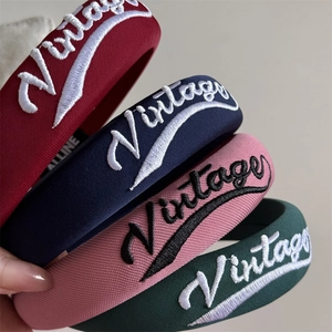 Close-up of four vintage embroidered thick headbands with retro lettering in various colors