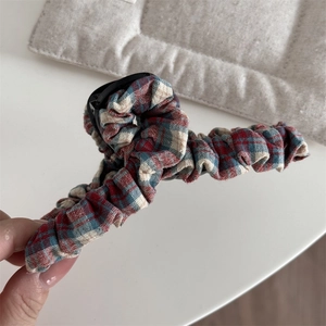 Close-up of red and green plaid fabric hair clip with vintage cotton texture details