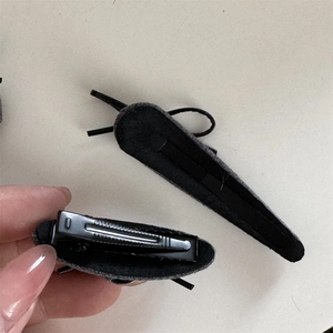 Détail de la pince à cheveux en tissu gris avec un clip bec de canard en métal