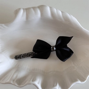 Vue détaillée de la barrette à nœud en satin noir avec centre en strass étincelants