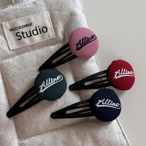 Set of four embroidered fabric button hair clips with Allure lettering on beige fabric